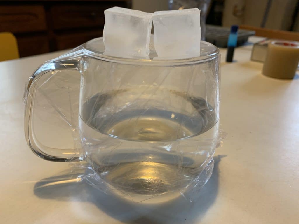 Les différents états de l'eau : un verre d'eau chaud avec deux glaçons posés dessus